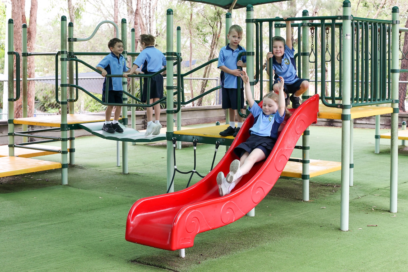 Students playing together on playground equipment, highlighting friendship, active play and wellbeing at Queen of Apostles Primary School