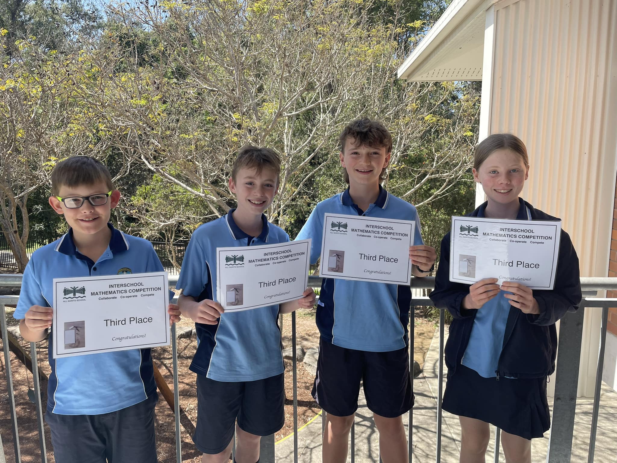 Students from Queen of Apostles Primary School holding certificates after achieving third place at a Catholic schools mathematics competition, highlighting teamwork, problem solving and academic achievement